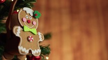 Gingerbread man decoration on a Christmas tree with falling snow and copy space