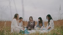 a women's group Bible study on a blanket in a field 