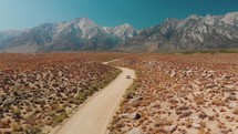 Drone flying towards Alabama Hills, car driving on small road