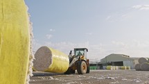 Large tractor loading cotton bales at a cotton gin before processing