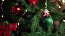 Ball with small Santa on it hanging from a Christmas tree 