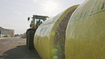 Large tractor loading cotton bales at a cotton gin before processing