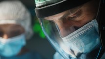 Surgeon with visor and surgical mask Operates A Contagious Disease