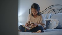 young woman reading a Bible in her lap in her bedroom 