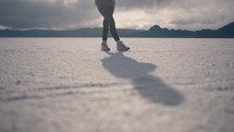 Young woman stands in sunny salt flats looking around
