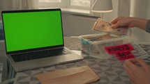 woman puts money in box savings build up a financial cushion for emergencies, retirement, or long-term goals on the table laptop with green screen
