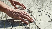 Hand touching drought cracked soil