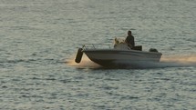 Man approaches harbor and quickly slows down on speedboat in golden sunset light, slow-motion