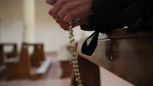 Woman Makes The Rosary Sitting Praying In Church For Peace