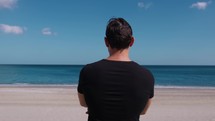 Boy Dressed In Black Observes The Sea On The Beach