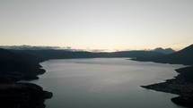 Still Lake Water And Majestic Mountain Silhouette Of Rostro Maya In Sundown - Aerial shot	