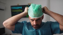 Surgeon wears green surgical cap