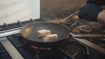 Cook is toasting breaded fish in a pan for second course lunch