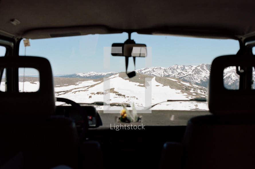 view of snowy mountains through a windshield 