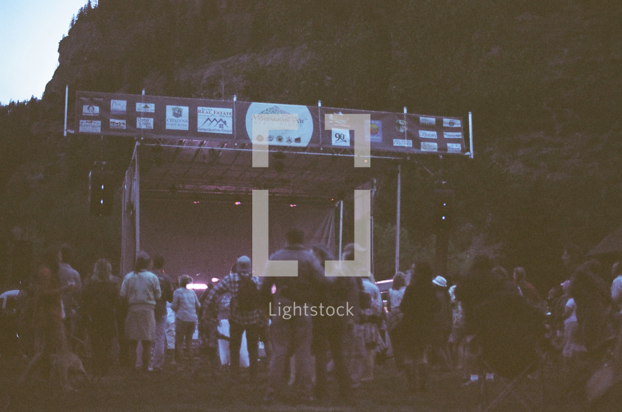 crowds around a stage at an outdoor music festival 