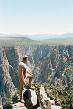 a man at the edge of a cliff overlooking a canyon 