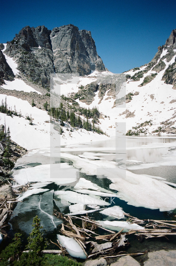 snow on a mountainside and ice in a lake 
