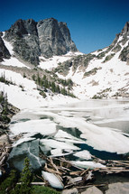 snow on a mountainside and ice in a lake 