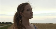 Closeup of a young woman worshipping, contemplating, praying outside in nature in a wheat field.