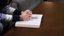 young woman praying with a Bible 