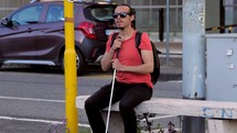 a blind man waiting at a bus stop 
