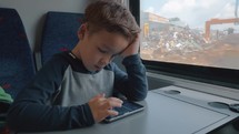 Boy using cellphone in train passing by the dump