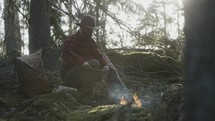 a man sitting near a fire in a forest 