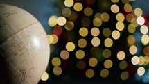 Globe rotating under Christmas tree lights background 