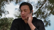 Seated Man In The Park Using Smartphone Under The Trees