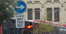 The red bus is stopped at the traffic light next to a road sign that says - Mandatory right turn, except for public transport, taxis, and bicycles. Rainy day, Valencia, Spain