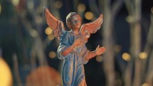 Close Up of an archangel with outstretched wings announcing the Nativity. Ceramic figure lit by the fire in the fireplace. Retro Christmas decoration. Dolly Shot and bokeh lights
