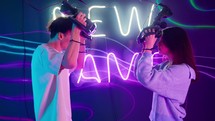 A man and woman face each other as they put on virtual reality goggles.
