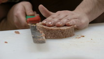 Cook slicing raw hamburger patties.