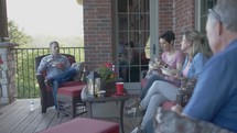 men and women sitting on a porch talking 