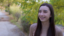 Teenager girl with braces laughing and smiling looking around and at the camera outside. Slow motion 4k