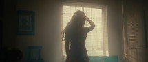 Asian woman dancing in a room with sunlight shining through the window
