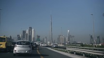 Cars driving toward city of Dubai and Burj Khalifa in morning for work on busy highway. Rush hour traffic - skyline, cityscape, skyscrapers.