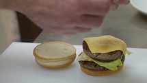 Cook assembling a cheeseburger at a restaurant.