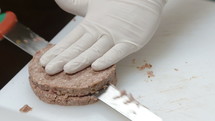 Cook slicing raw hamburger meat.