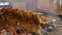 Chicken being cooked over coals.