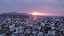 Aerial Dolly Over Ksamil Riviera With View Of Stunning Orange Sunset On Horizon. Establishing Shot