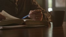 a man reading a Bible during his morning Bible study and taking notes.