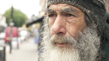 Close up of a gray bearded man on the street.