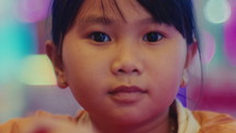 Close-up of the face of a small Asian girl intently playing a game
