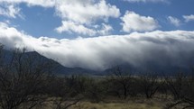 Timelapse of rolling clouds and fog over a desert mountain range
