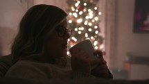 a woman sipping from a mug at Christmas 