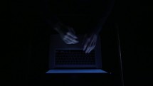 man opening a laptop and typing in darkness 