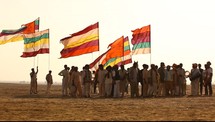 tribesmen holding flags standing in a desert 
