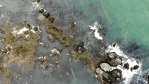 aerial view over ocean water washing onto rocks in Ireland 