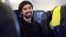 Man enjoying his journey by airplane, smiling to the camera.